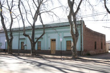 Kırmızı tuğladan yapılmış eski bir koloni tarzı ev ve kırsal bir kasabada su yeşili bir cephe. Eski binalarla sokak manzarası.