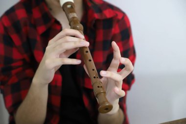 Teenage girl playing the recorder, music classes. Student taking music lessons. Wind instrument. Background with copy space. clipart