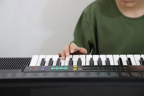 Çocuk elektrikli klavye çalıyor. Müzik sınıfında ergen. Arka planda fotokopi alanı olan müzik dersleri. Sınıflarda öğrenci.