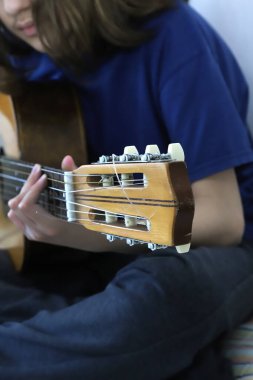 Student playing classical guitar. Boy in music lessons. Stringed instrument. Background with copy space. Vertical image. clipart