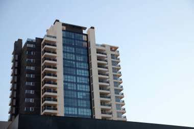 Camlı pencereleri ve balkonları olan modern bina ve arka planında gökyüzü olan fotokopi alanı olan bir bina. Emlak.