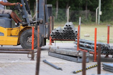 Forklift inşaat malzemelerini gün ışığında bir şantiyeye taşıyor.