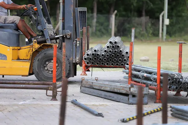 Forklift inşaat malzemelerini gün ışığında bir şantiyeye taşıyor.