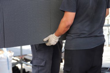 Müzik prodüksiyonunda çalışan erkekler. Rock etkinliği için dev LED ekran panelleri montajında çalışan teknisyen. 