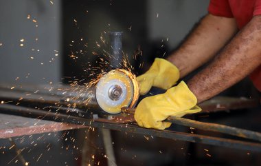 Demirci dükkanında çalışan bir adam. Demirci manuel öğütücüyle demir kesiyor..