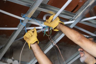 Elektrik tesisatçısının inşaat halindeki binaya kablo döşemesi