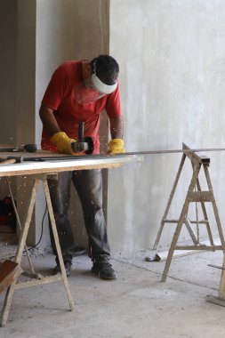 Atölyesinde elektrikli öğütücüyle demir kesen Latin bir demircinin dikey fotoğrafı.