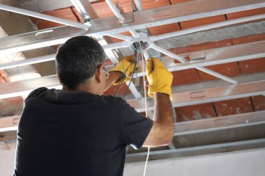 Electrician working on the light wiring of a home clipart