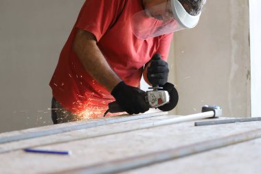 Latin demirci atölyesinde elektrikli değirmenle demir kesiyor.
