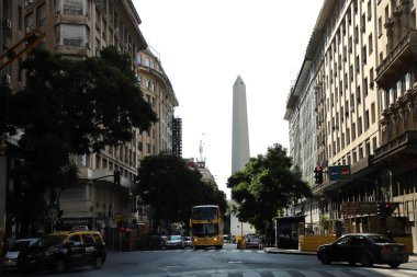 Arjantin 'in Buenos Aires şehrinin sokak manzarası. Arka planda Obelisk ve arabalar, taksiler ve otobüsler dolaşıyor..