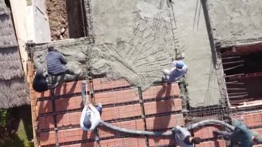 Masonlar bir evin çatısına çimento döşüyorlar. İnşaat sektöründe çalışan erkekler. 
