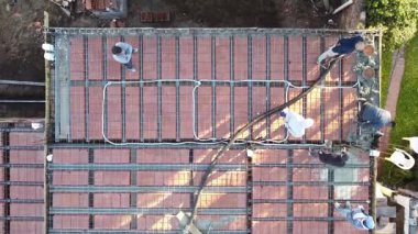 Bir evin çatısına çimento döşeyen adamların robot videosu. İnşaat işçileri binanın çatısına beton döşüyorlar..