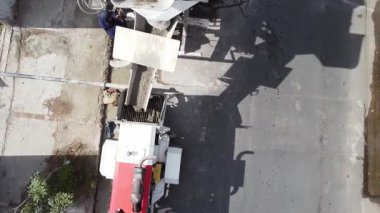 Çimento karıştırıcı kamyonunda çalışan adamların hava aracı videosu. Çimento kamyondan hortuma boşaltılıyor.