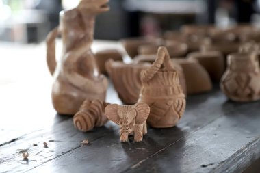 Ön planda fil figüründen yapılmış el yapımı seramik parçalar ve arka planda vazolar ve çömlekler.