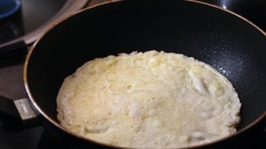 Bir adam kızartma tavasında pişen bir krepi çeviriyor. Yemek pişiriyorum, yakın plan..