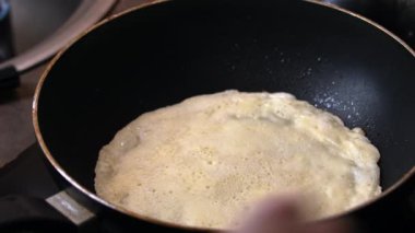 Bir adam kızartma tavasında pişen bir krepi çeviriyor. Yemek pişiriyorum, yakın plan..