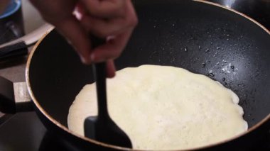 Bir adam dikkatsizce ve dikkatsizce krep hazırlar. Krep kırışıyor ve tavada iyi dönmüyor..