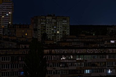 Kyiv, Ukrayna - 05.15.2024. Gece elektrik kesintisi sırasında paneldeki konut binalarına bakın. Arka planda koyu mavi bir gökyüzü. Rusya 'nın füze saldırısından sonraki sonuçlar. 