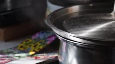 Kapağı kapaklı kaynar su tenceresi, kapağın altından buhar ve su fışkırıyor. Ev mutfağı, ocakta unutulmuş bir tava..