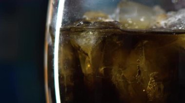 Buzlu kola kokteyli. Yan bakış açısı. Kola yavaşça masanın üzerinde dönüyordu ve camın çok yakından görüntüsü vardı. Baloncuklar çıkıyor. Klasik viski, rom kokteyli. Soğuk, ferahlatıcı içecek.