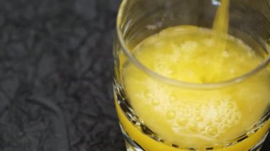 Portakallı gazoz bardağa döküldü, sonrasında buz küpleri içeceğe eklendi. Portakal suyu ve buz olan bir bardağın yakın görüntüsü. Baloncuklar çıkıyor. Soğuk, ferahlatıcı içecek.