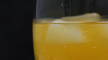 Buzlu portakallı soda. Yan bakış açısı. Portakallı gazozun yavaşça masada döndüğü cam manzarayı çok yakından izleyin. Baloncuklar çıkıyor. Soğuk, ferahlatıcı içecek.