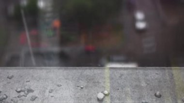 Şiddetli yağmur ve dolu pencerenin dışına yağar. Demir pencere eşiğine dolu yağar. Arka planda bulanık sokak. Kötü hava durumu konsepti.