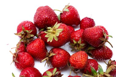 Beyaz bir fincan tabağında taze olgun doğal çilek yığını. Taze toplanmış bahçe çilekleri. Soyut bir arkaplanda çileklerin detaylı fotoğrafı. Görüntüyü kapat