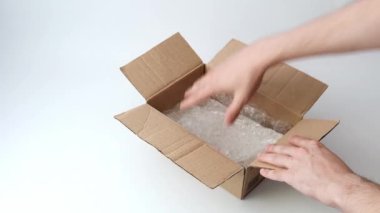 Adamın elleri, içinde kırmızı kurdele olan beyaz bir taşın teslimatı için bir karton kutuyu açıyor. Sahte teslimat konsepti. Yanlış dağıtım kavramı.