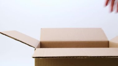 Eller teslimat için açık karton kutudan hediye kutusunu alır. Beyaz bir arka planda. İzole edilmiş. Teslimat konsepti.