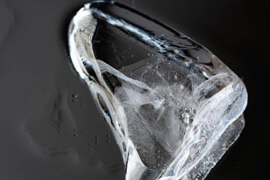 Karanlık ayna arka planında yansıması olan soyut bir buz parçası. Buz kütlesi izole edildi. Suyun altında. Macro dünyası. Dokulu parlak buz yüzeyi