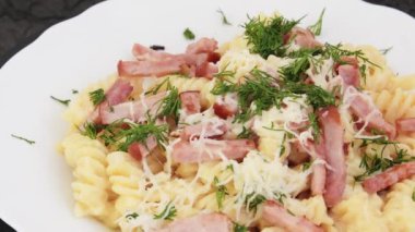 Beyaz çay tabağında makarna, peynir ve dereotlu makarna. Döndürme etkisi. Ev yemeği konsepti.