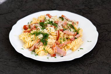 Beyaz çay tabağında makarna, peynir ve dereotlu makarna. Döndürme etkisi. Ev yemeği konsepti. 