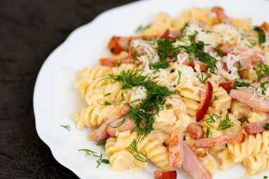 Beyaz çay tabağında makarna, peynir ve dereotlu makarna. Döndürme etkisi. Ev yemeği konsepti. 