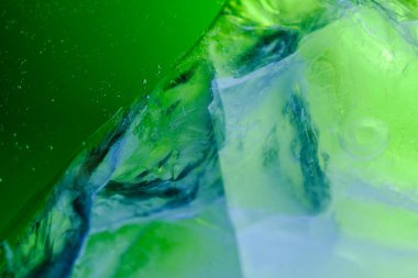 Buz kütleli soyut su arkaplanı. Yeşil parıltı. Su kabarcıkları yükseliyor. Suyun altında. Macro dünyası. Desenli.