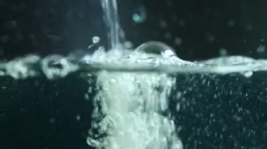 Soyut su arka planı. Su yüzeyinde su akıntısı var. Su kabarcıkları yükseliyor. Suda parlayan toz parçacıklarını kaotik bir şekilde hareket ettiriyor