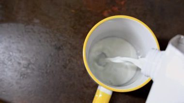 Kağıt torbadan bir kaba süt dökmek. Üst Manzara. Ahşap masa arkaplanı. 