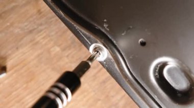  Sabit disk kapağını tornavidayla açıyorum. Torx vidasını sabit diskten sökmek. Manzarayı kapat. Arka planda tahta bir masa. Bilgisayar donanım onarımı