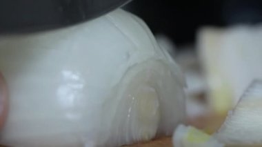 Soğanı kesen bir bıçağın yakın plan görüntüsü. Tahtada bıçakla soğan doğramak. Soğan doğruyorum. Evde yemek pişirme, yemek hazırlama, mutfak teknikleri.. 