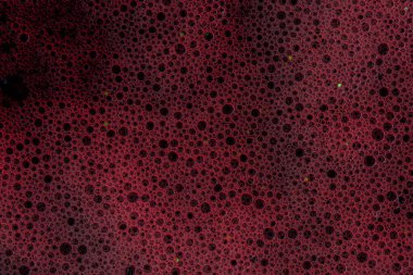 Baloncuklu köpük sıvısının yakın çekim görüntüsü, canlı kırmızı ışıkla aydınlatılıyor. Soyut arkaplan, duvar kağıdı