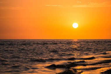 Denizin üzerinde gün doğumu dalgalarla denizi aydınlatan parlak bir ışıkla