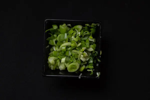 Salatalıklı yeşil salata ve siyah arka planda yeşiller.