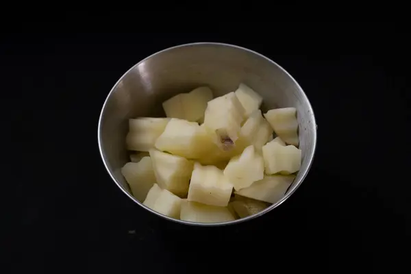 Siyah arka planda kasede taze patates kes.