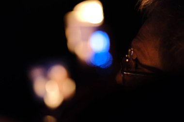 Yakın plan. Karanlık odada arka planda bulanık bir mikrofonu tutan bir adamın eli..