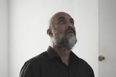 Kel sakallı olgun bir adam başka tarafa bakıyor.