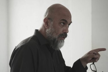 Siyah gömlekli, beyaz arka planda siyah gömlekli kel bir adam.