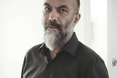 Sakallı ve bıyıklı orta yaşlı bir adamın fotoğrafına bakıyorum.