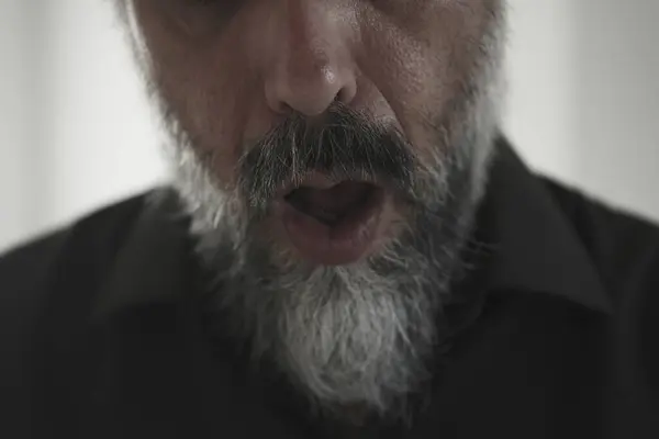Siyah arka planda sakallı bir adam portresi