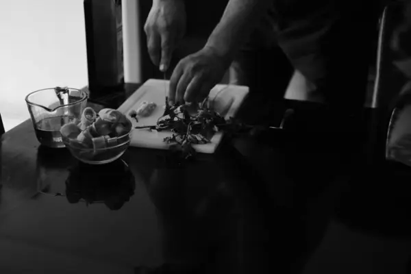 Yemek yapan bir adamın siyah beyaz fotoğrafı.