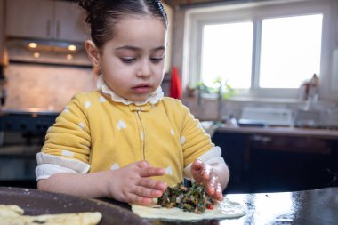 Torun, büyükannesine mutfakta hamur işi yapmada yardım ediyor. Anne duyguları seviyor.